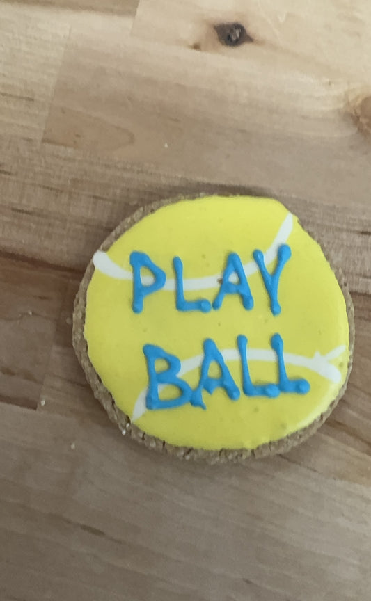 Round yellow object with 'PLAY BALL' text on a wooden surface